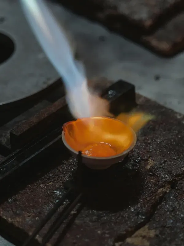 Gold melting in a dish under the torch, on a jeweler's bench